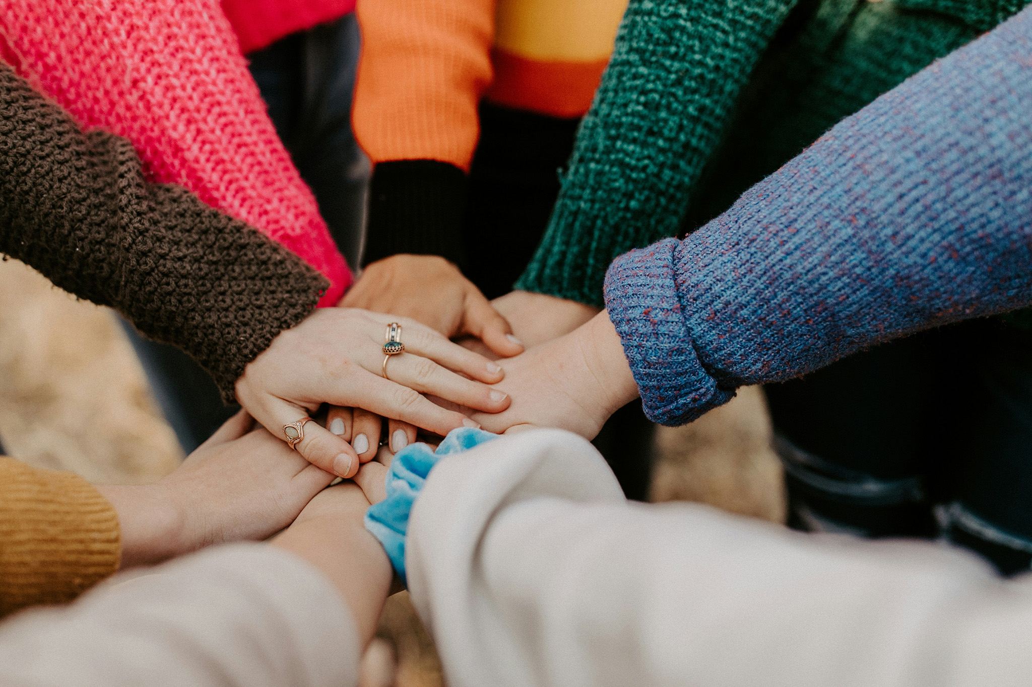 A bunch of people putting their hands in a circle joining together for a common goal